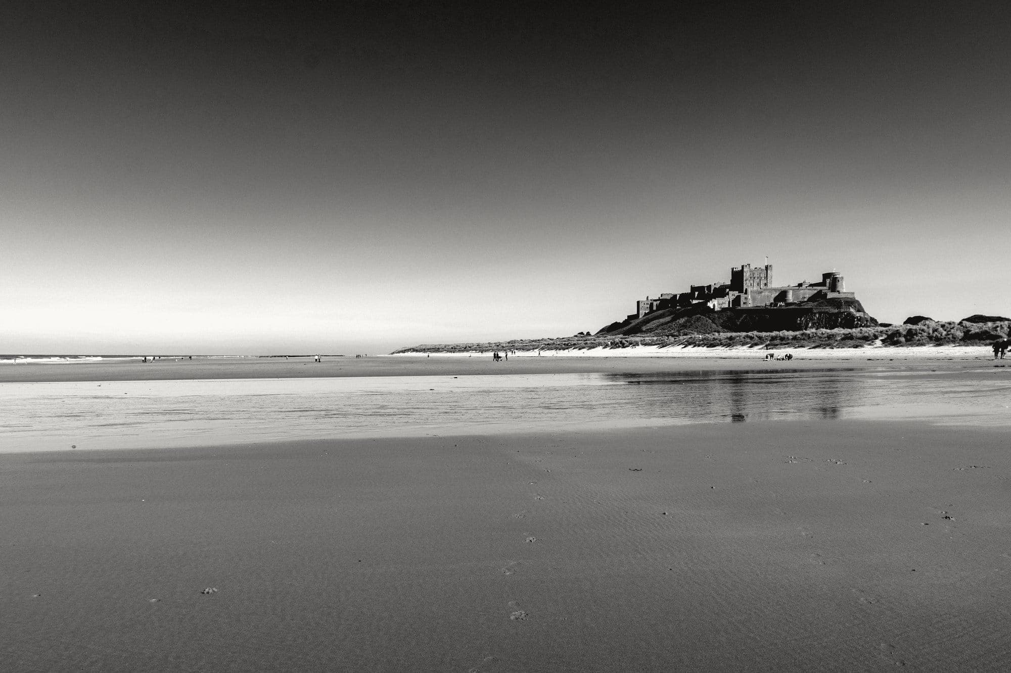 A castle on a rock above a wide, empty beach