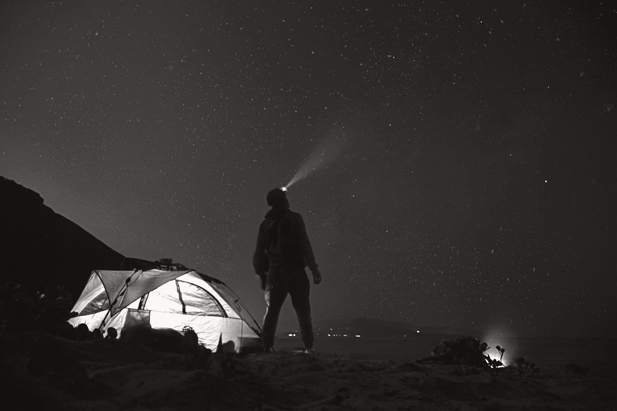 A glowing tent under a starry sky