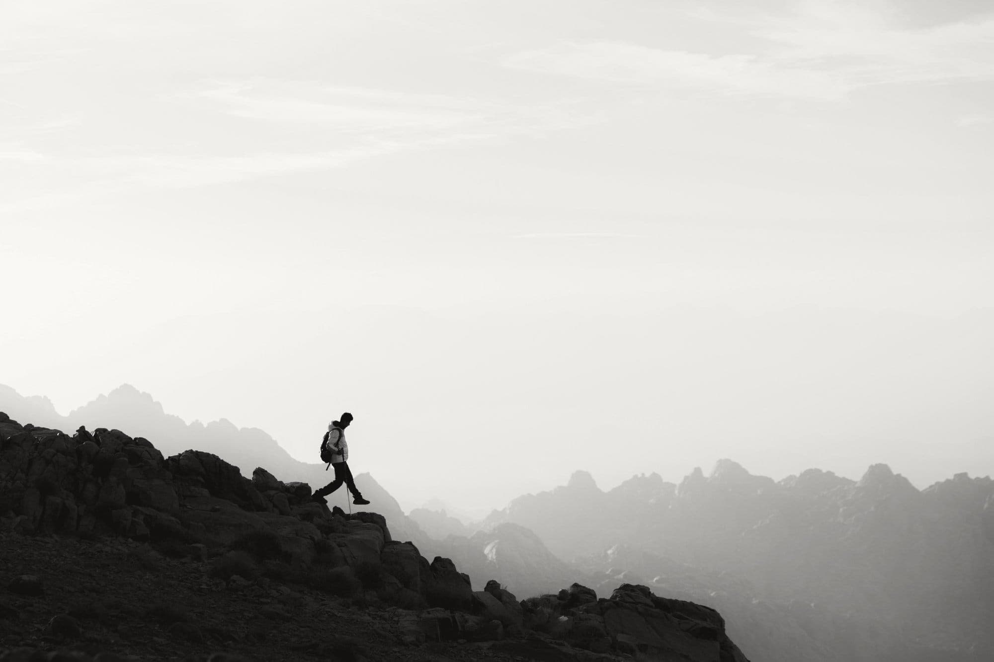 A walker descending a mountain ridge into the haze