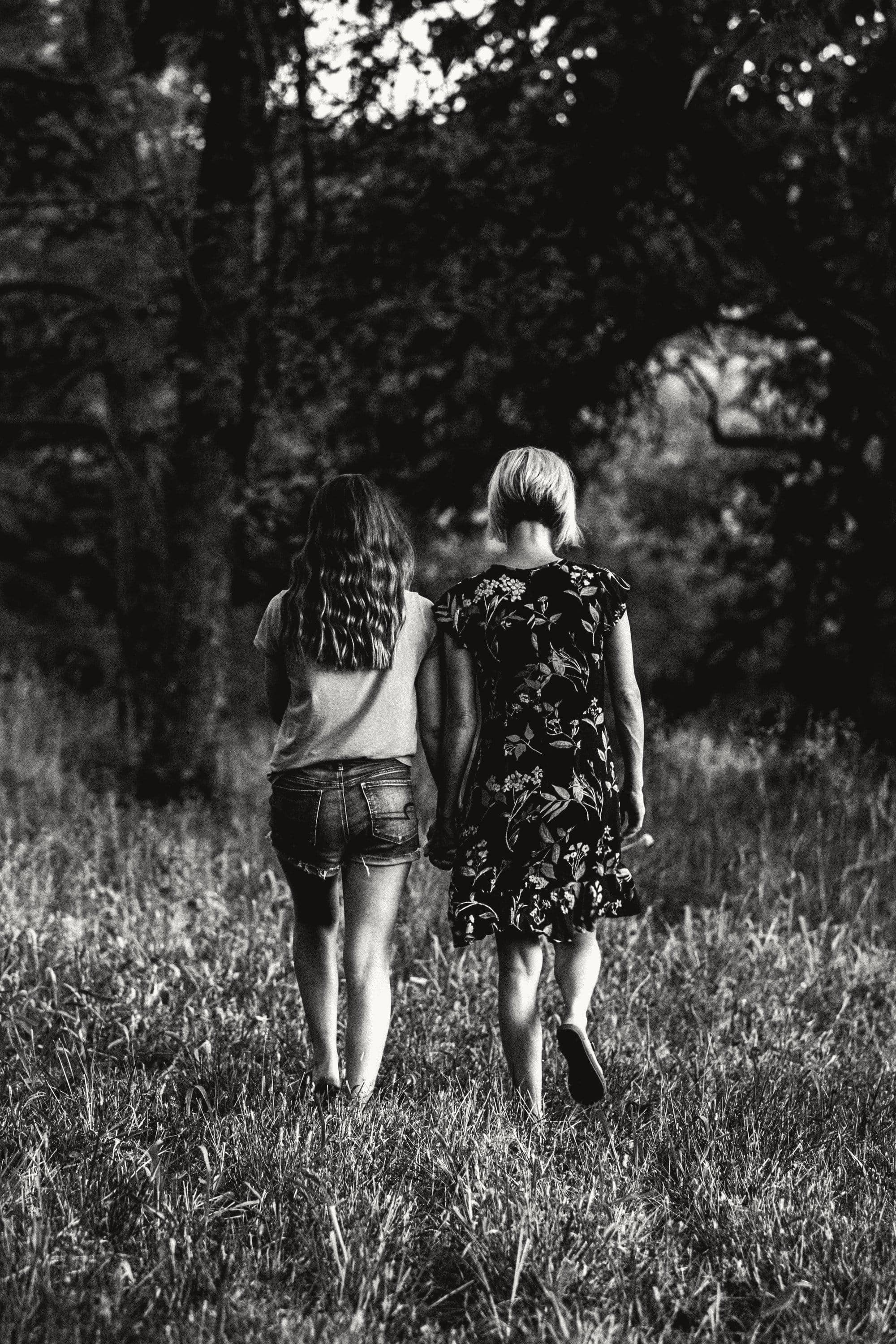 A mother and daughter walking away together through long grass